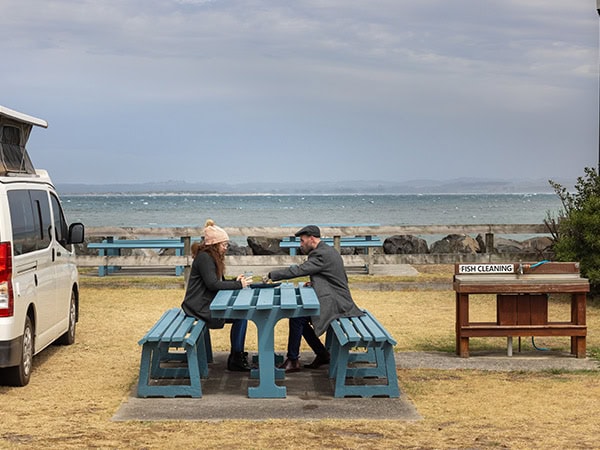 a couple sits on picnic bench at Tatlow Beach, BIG4 Stanley Holiday Park