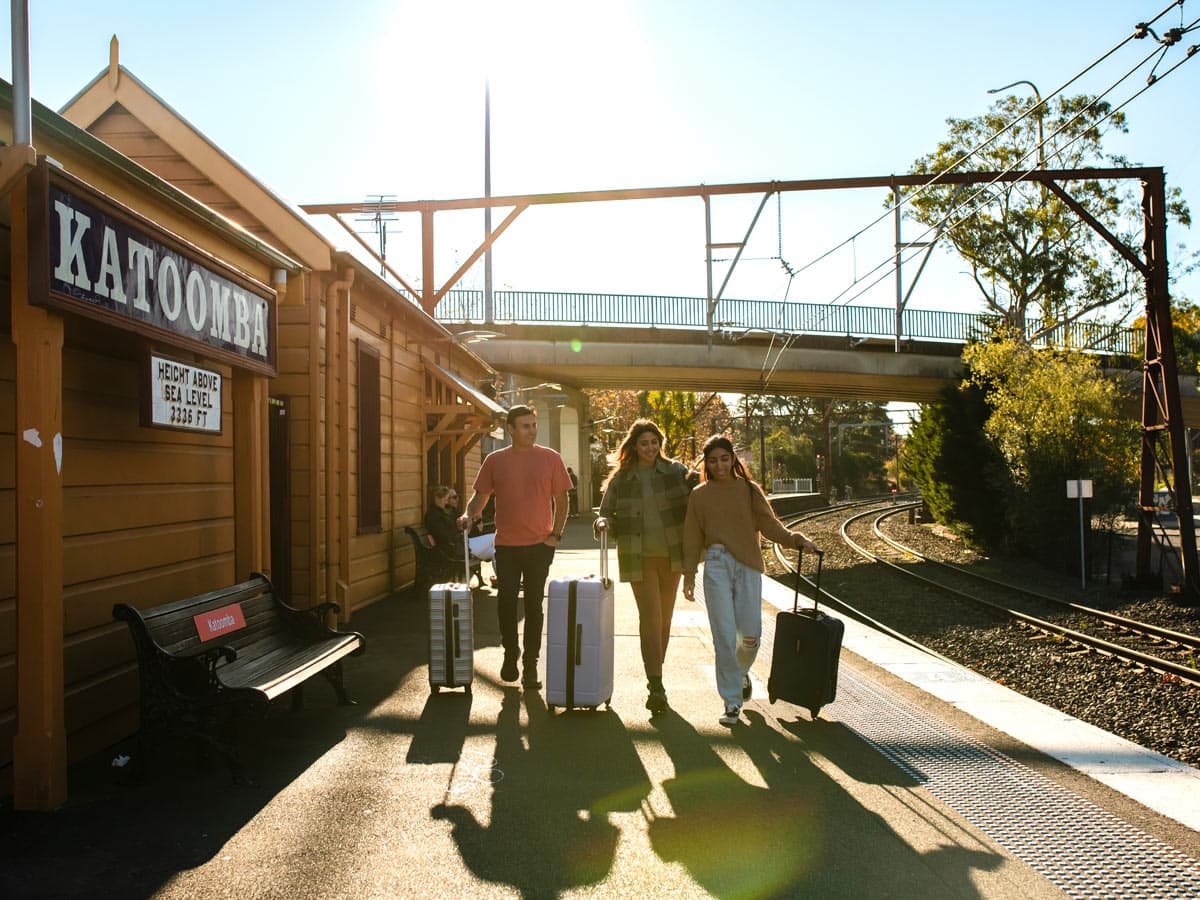 Young people with luggage catching a train at Katoombatrain station.