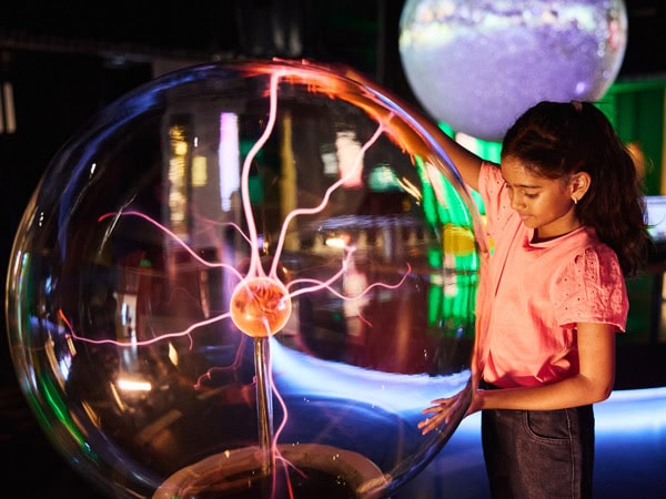 a little girl getting her hands on an interactive exhibit at SparkLab