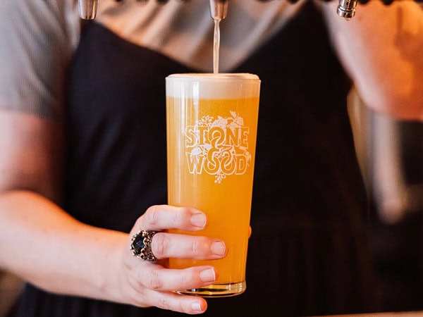 a woman filling up a glass of beer on tap at Stone & Wood Brisbane