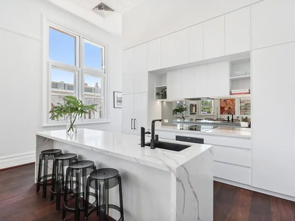 the whitewashed kitchen and dining area with a huge window at 1853 Market Airbnb in Fremantle