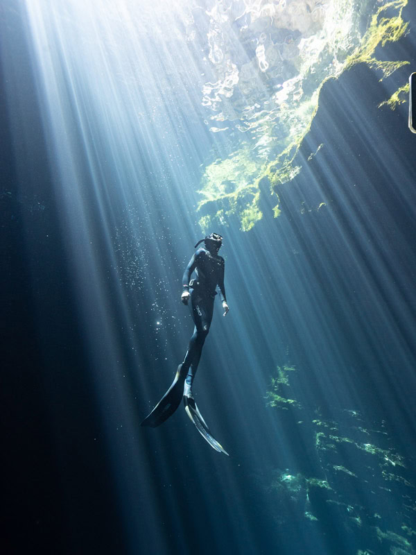 a diver facing the light as it passes through the water under Kilsby Sinkhole