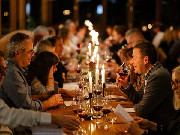 group of people enjoying a candle-lit long table dinner at