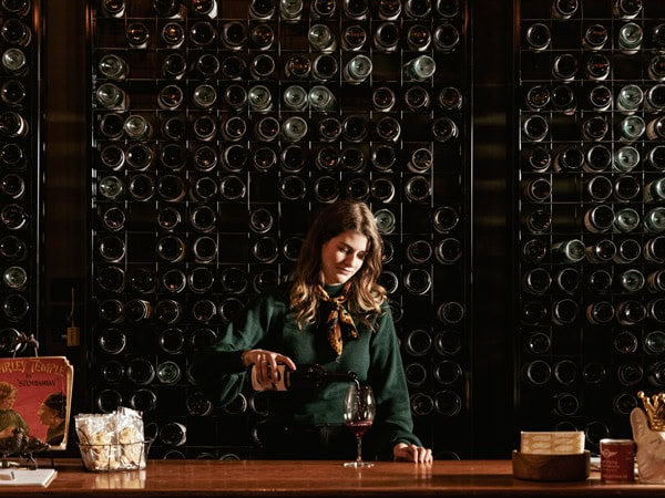 a woman pouring wine into a glass inside the cellar door of Shut the Gate Wines
