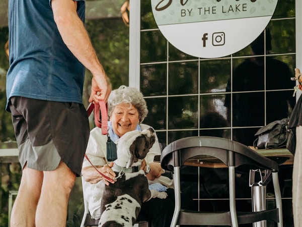 an old lady petting a dog outside Stellas by the Lake cafe in Canberra