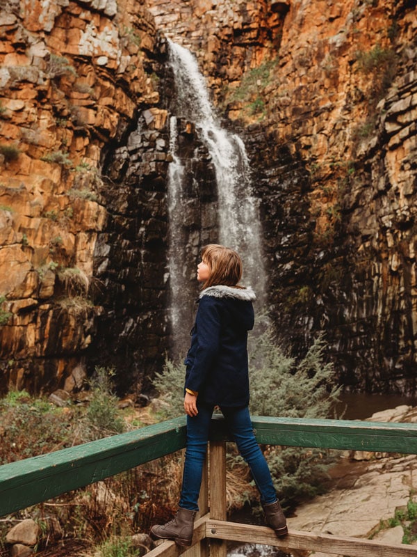 a girl posing for a photo with Three Falls as her backdrop