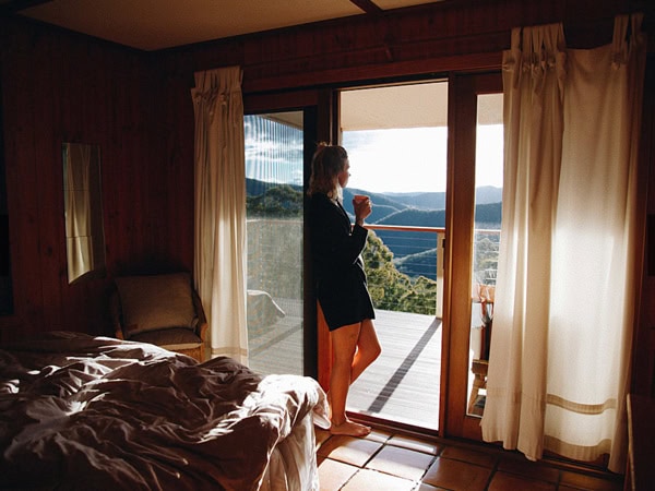 a woman admiring the mountain views from her window while sipping coffee at Turon Gates Mountain Getaway