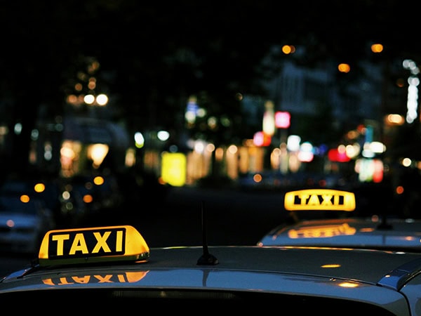 lights on top of two taxis against city lights