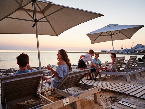 people relaxing on sunloungers with a drink in hand at Bathers Beach