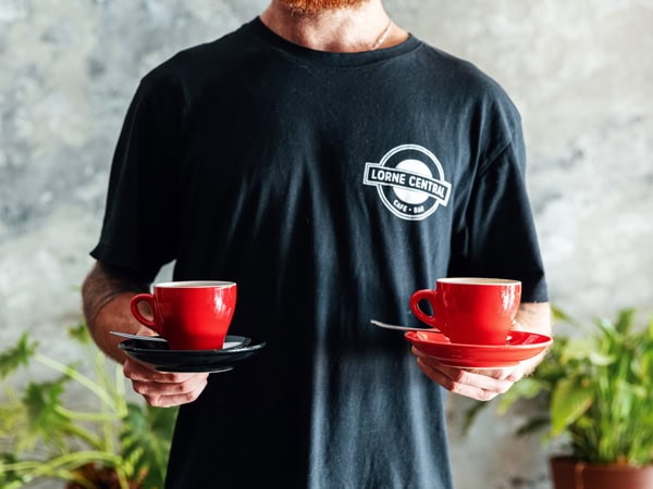 a man holding two red cups of coffee at Lorne Central