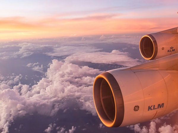 Plane engine as aircraft flies above clouds