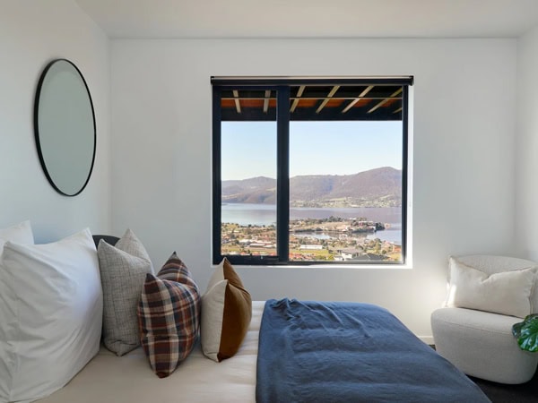 a whitewashed bedroom at Rosetta Heights with a window showing scenic mountain views in Hobart