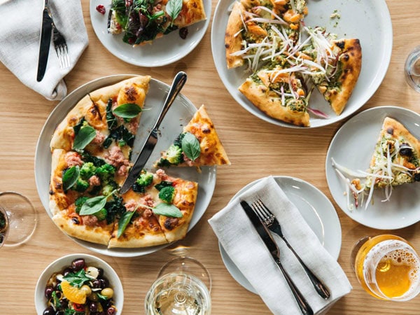 a spread of pizza alongside drinks on the table at 2KW, Adelaide