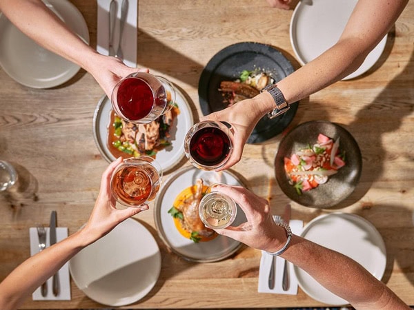 holding drinks over a spread of food on the table at Conlan’s Wine Store, Port Fairy