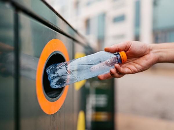 Close-up of a young man putting a water bottle in a recycling bin in Malmo in Sweden.