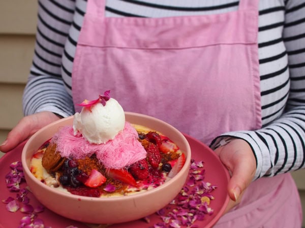 a cafe staff in pink apron holding a bowl of pink food at Harrow and Harvest Cafe