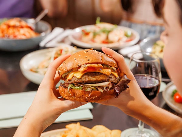 a hand holding a burger at the QA Hotel in Brisbane