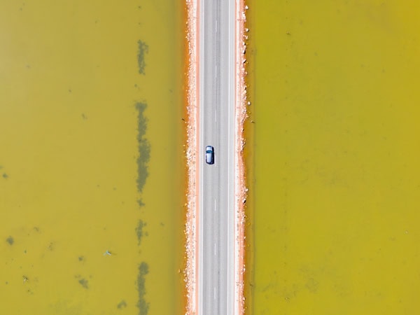 an aerial view of a car driving on the road along Quairading Pink Lake