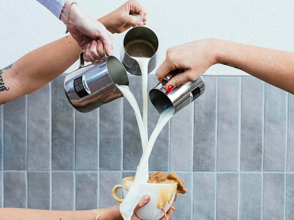 hands pouring milk into a cup of coffee at Abacus Espresso, Perth
