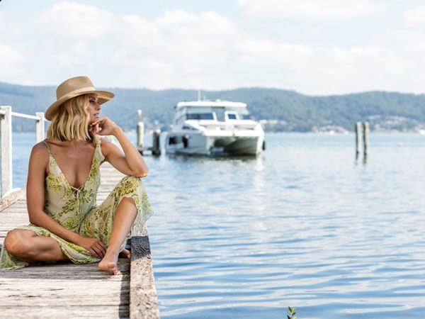 A woman overlooking a pier while in a wide brimmed travel hat.