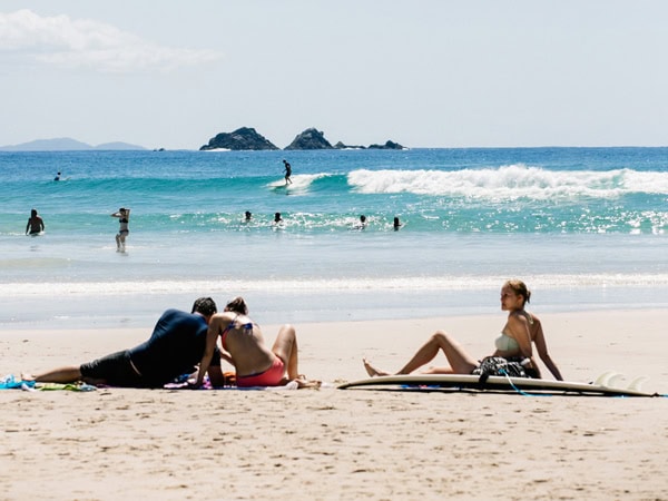 surfers sitting on the beach at Byron Bay