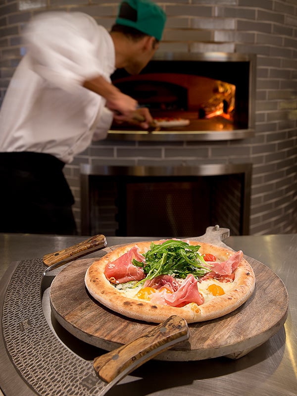 chef putting pizza into woodfired oven at Cucina Vivo