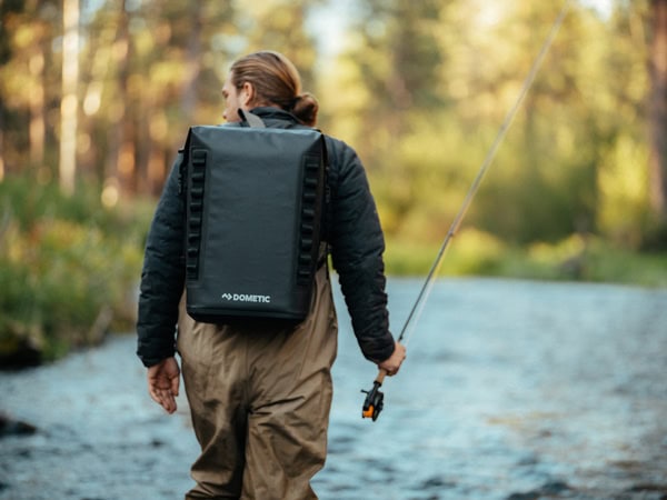 A man holding a fishing rod with the Dometic backpack on.