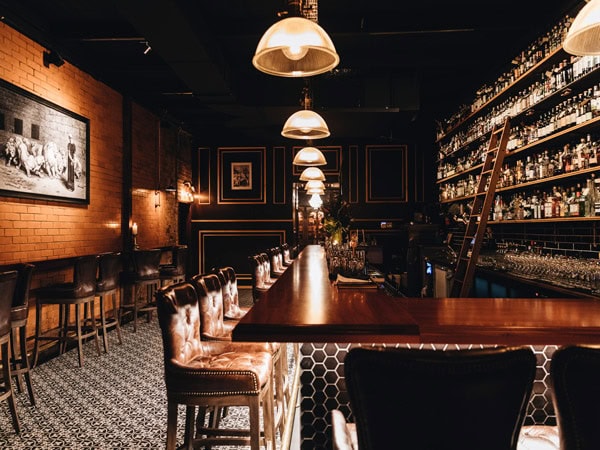 the dimly lit bar with empty stools at Death & Taxes, Brisbane