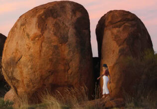 A woman standing in the Devil's Marbles.