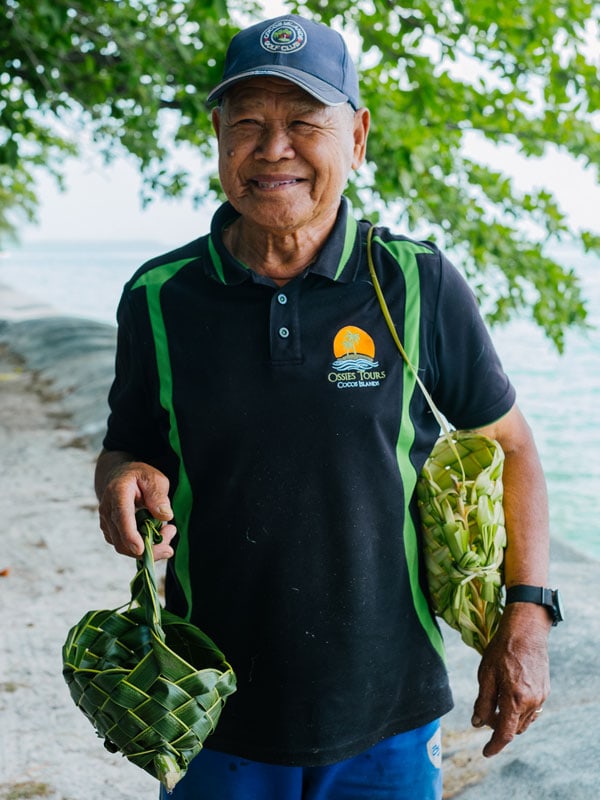 a local guide carrying weaved baskets during the Home Island Cultural Tour, Cocos Keeling Islands