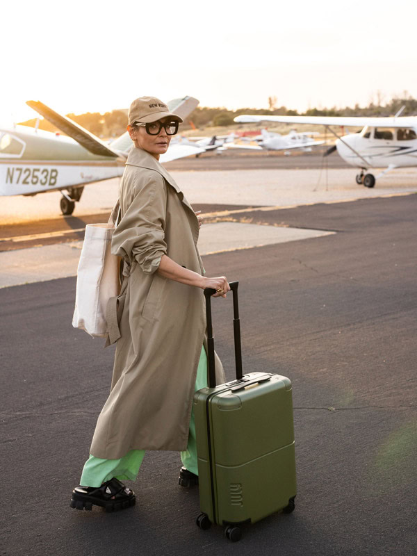 A woman about the catch a plane wheeling her July carry-on luggage 