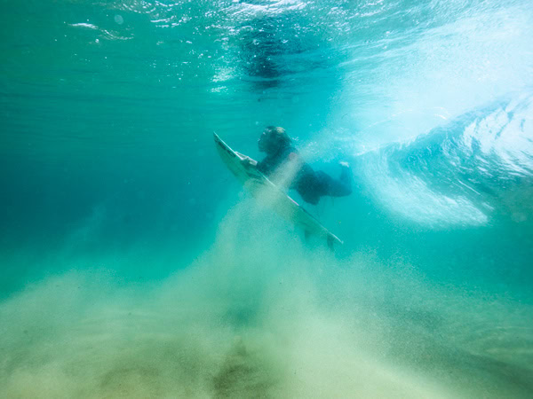 a surfer duck-diving under a wave at North Narrabeen Beach