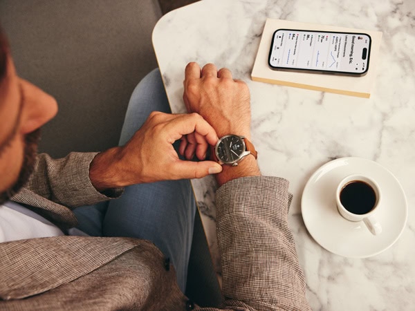 A man enjoying a cup of coffee while using his ScanWatch to track his heart rate