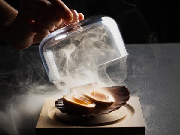 a hand taking out the cover of a smoky dish at Taro’s Ramen