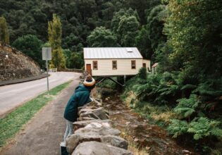 A woman on the edge of a road with Walhalla ghost town in the background