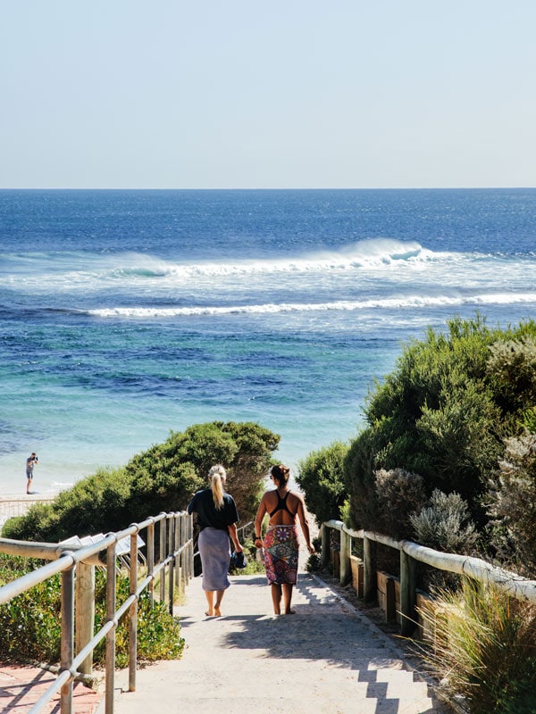 two women walking down the beach staircase at Yallingup Beach