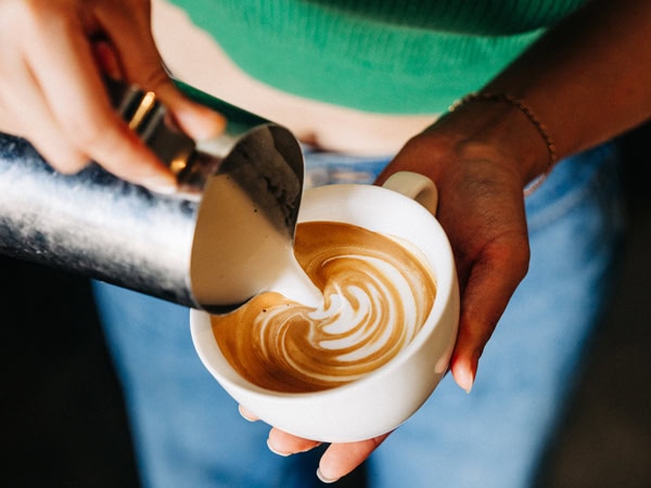 milk pouring over a cup of latte at Community Coffee in Perth