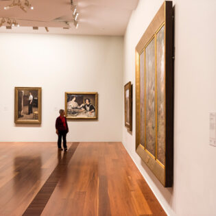 a man looking at artworks on the wall inside The Ian Potter Centre: NGV Australia, CBD