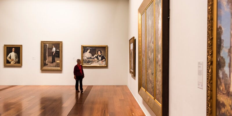 a man looking at artworks on the wall inside The Ian Potter Centre: NGV Australia, CBD