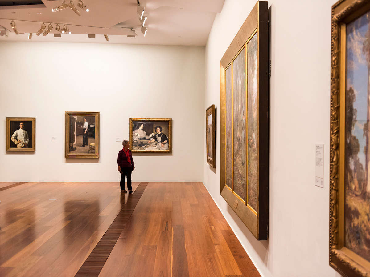 a man looking at artworks on the wall inside The Ian Potter Centre: NGV Australia, CBD