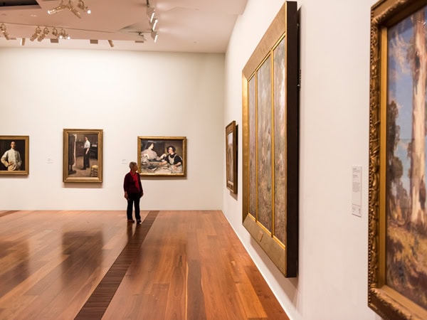 a man looking at artworks on the wall inside The Ian Potter Centre: NGV Australia, CBD