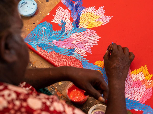 a woman making Aboriginal Art at Ikuntji Artists, Haasts Bluff