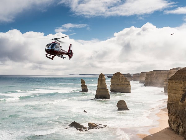 a helicopter flying above the Twelve Apostles