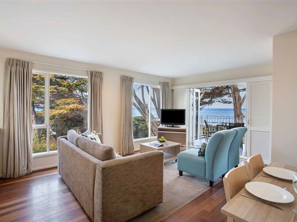 a living room with windows looking out to the sea at Mantra Lorne
