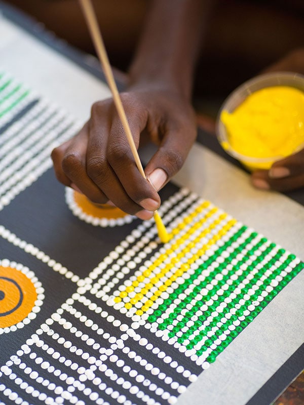 a hand doing a Maruku Art Dots Painting in Uluru