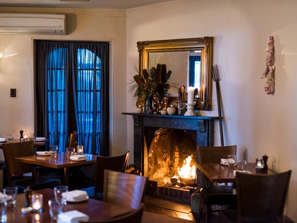 a dining room with a fireplace at Merrijig Inn in Port Fairy