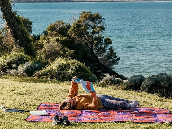 a girl lying on a blanket while reading a book