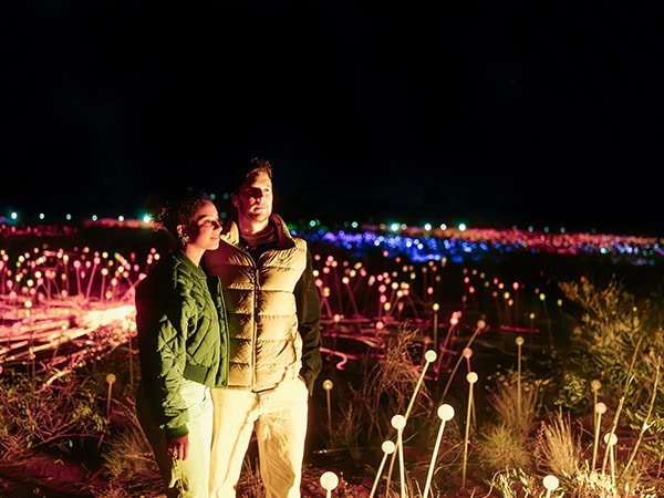 couple walking through Field of Light art installation in uluru