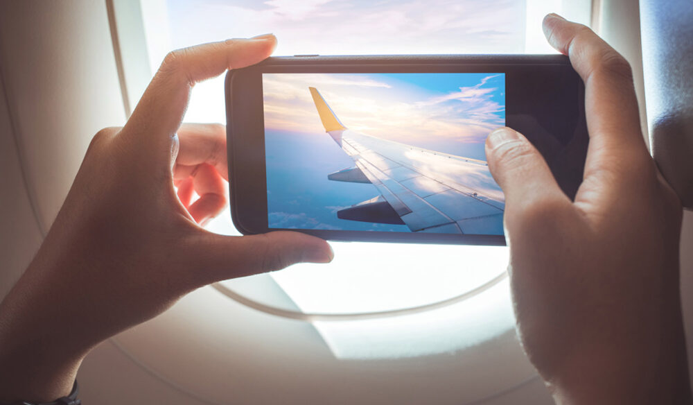 person taking a photo out of the plane window while in flight