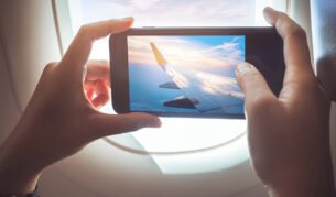 person taking a photo out of the plane window while in flight